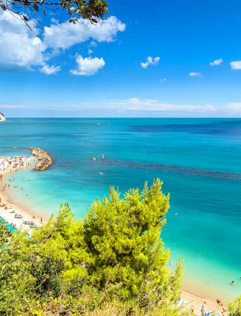 Tagesansicht des beruehmten Strandes voller Touristen in Sirolo, Italien | © Gettyimages.com/eddygaleotti