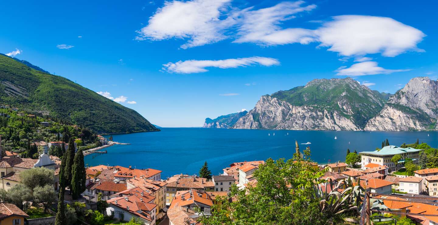 Der Gardasee von der Aaussichz eines Berges aus.Unten ist ein Dorf zu sehen, der Himmel ist blau | © Gettyimages.com/zodebala