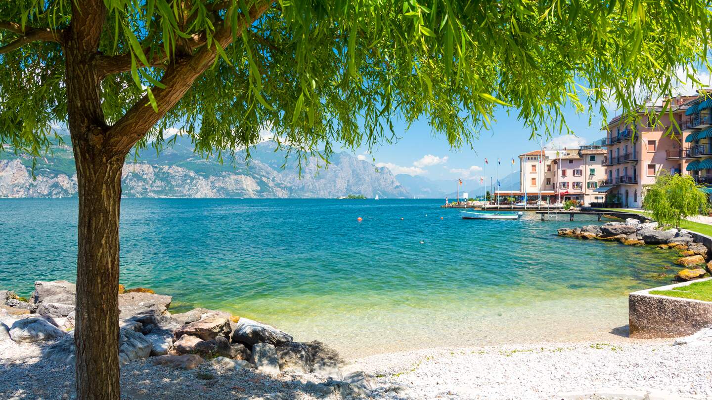 Auf dem Bild sieht man den See mit den felsigen Bergen im Hintergrund. Ein Baum ragt von links in das Bild | © Gettyimages.com/milenapigdanowicz-fidera