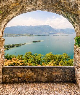Blick von einem Felsbalkon auf den Gardasee und Berge im Hintergrund | © © Gettyimages.com/bwzenith