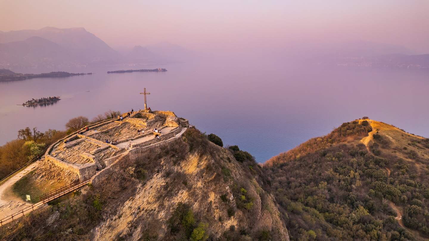 Luftaufnahme der Festung mit einem Kreuz auf einem Huegel im Hintergrund Gardasee. Panorama auf die Rocca di Manerba Draufsicht | © Gettyimages.com/fedevphoto