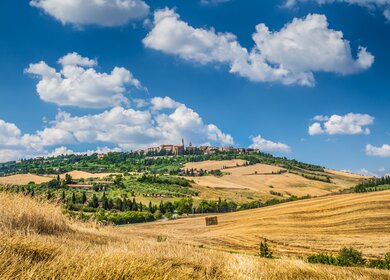 Huegelige Landschaft im Val d'Orcia mit Blick auf die Stadt Pienza | © Gettyimages.com/bluejayphoto