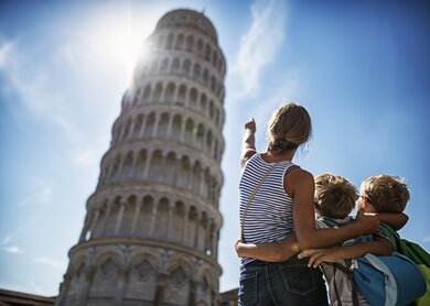 Touristenkinder bei der Besichtigung von Pisa, Italien. Brueder und Schwester stehen auf der Piazza del Miracoli und bewundern den beruehmten schiefen Turm von Pisa. | © Gettyimages.com/imgorthand
