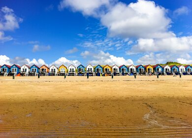 Bunte Strandhaeuser am Strand mit Blick aufs Meer | © Gettyimages.com/elenaestelles
