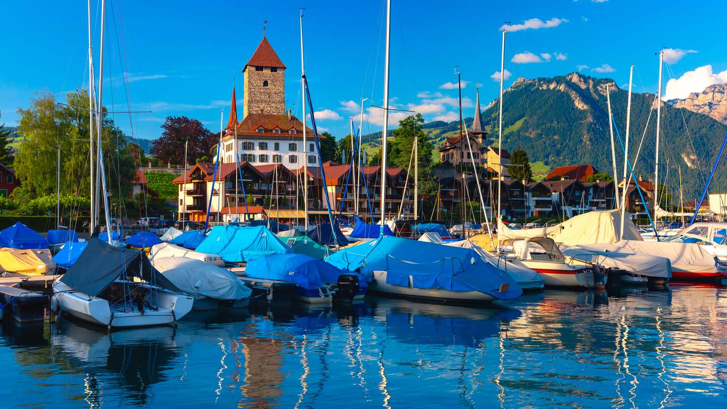 Kirche und Schloss Spiez am Ufer des Thunersees in der Region Berner Oberland im Schweizer Kanton Bern bei Sonnenuntergang | © gettyimages.com/KavalenkavaVolha