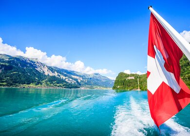 Blick auf den brienzer See von einem Boot aus, rechts sieht man wie die Schweizer flagge weht. | © Gettyimages.com/Vichai Phububphapan