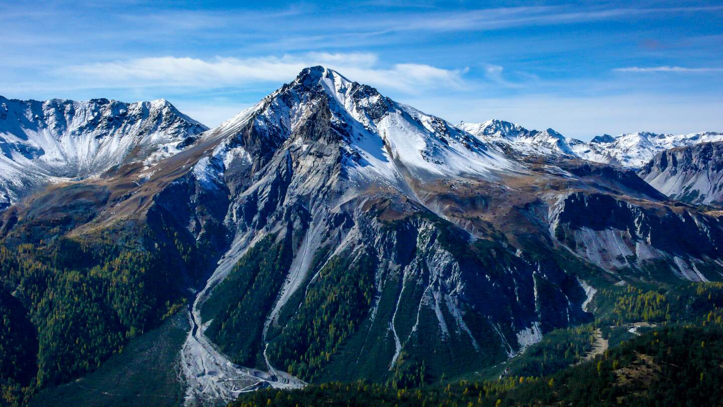 Blick in ein bewaldetes Tal aund auf schneebedeckte Berge im Schweizer Nationalpark nahe Zernez, Graubünden | © GettyImages/makasana