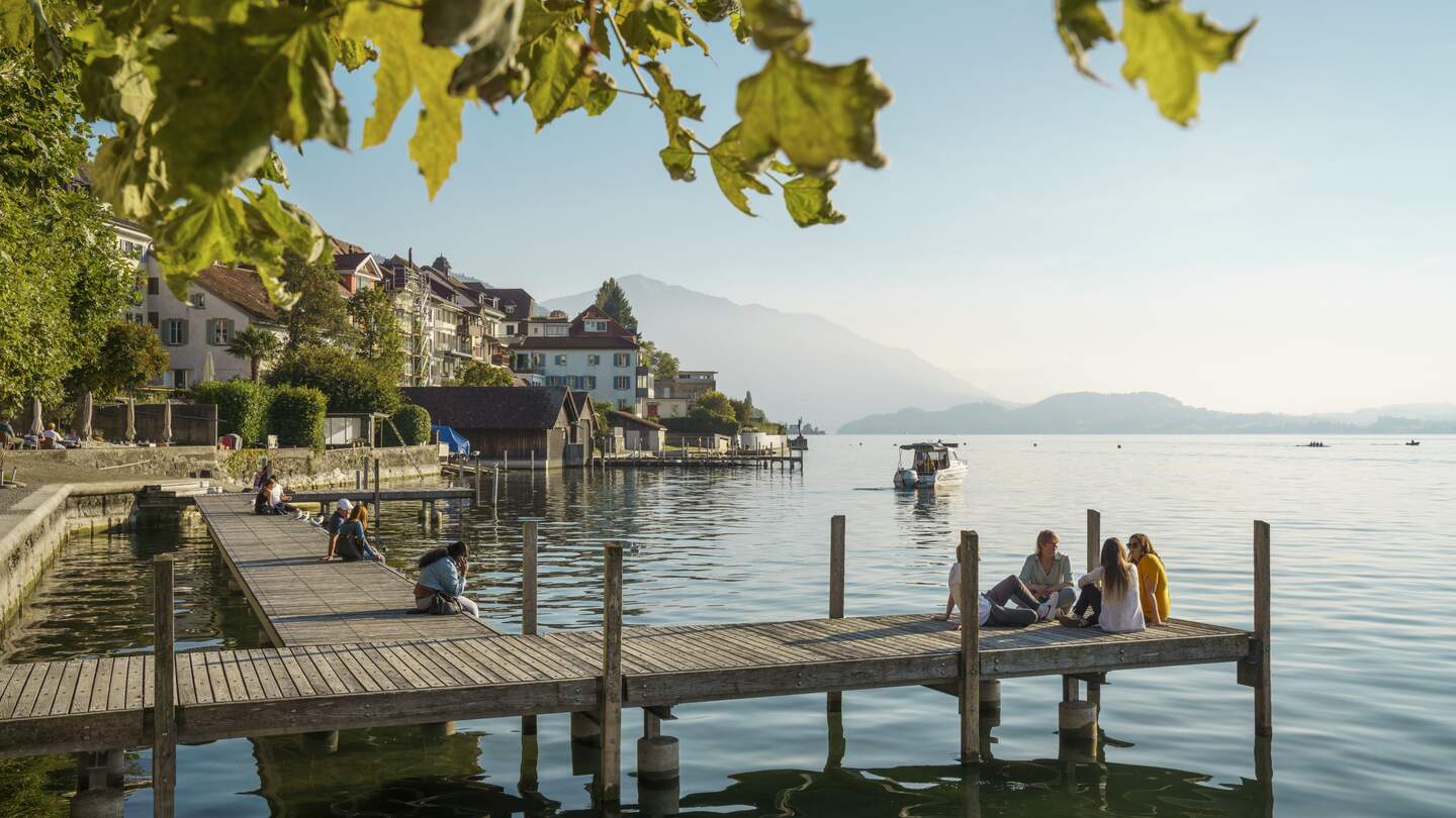 Gruppe geniesst die Abensonne auf dem Schiffssteg am Gärbliplatz in Zug. | © Schweiz Tourismus/Andre Meier