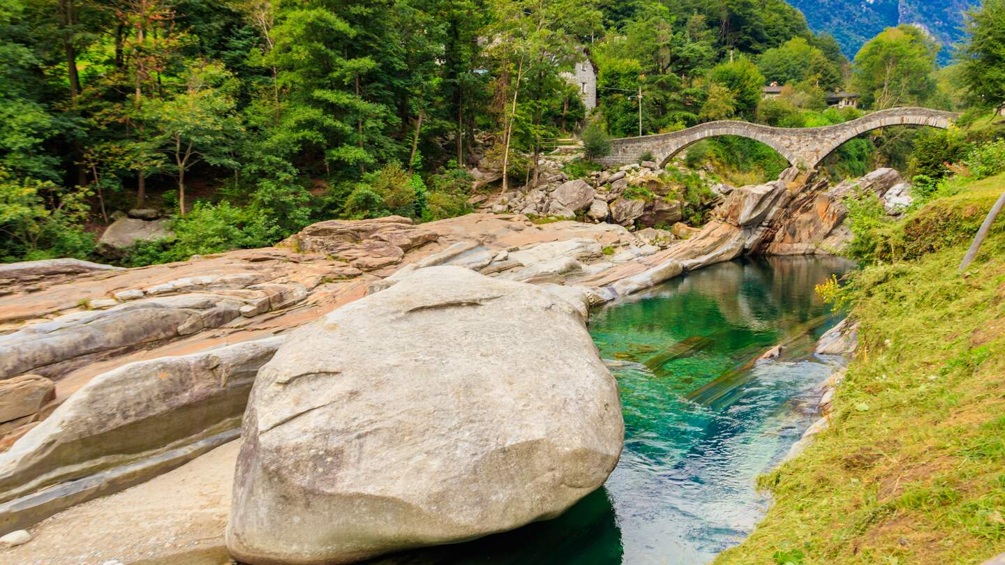 Antike roemische Doppelbogensteinbruecke (Ponte dei Salti) ueber das klare Wasser des Flusses Verzasca in Lavertezzo, Verzascatal, Kanton Tessin,  | © Gettyimages.com/olyasolodenko