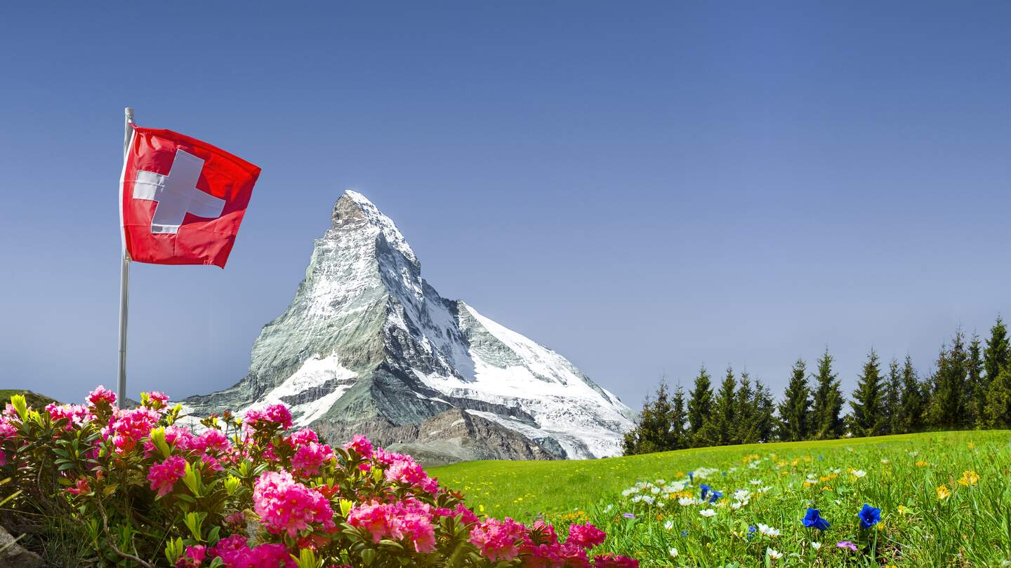 Schweizer Flagge mit Matterhorn und Bergwiese | © gettyimages.com/by-studio