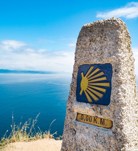 Meilenstein am Leuchtturm von Finisterre, dem Ende des Jakobswegs | © 	naphtalina/Gettyimages.com