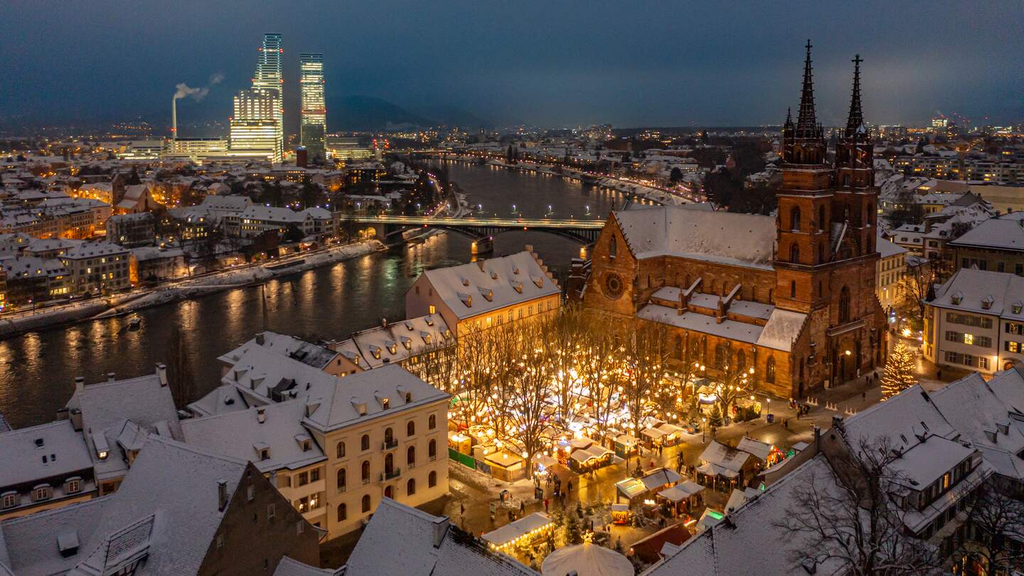 Beleuchteter Weihnachtsmarkt vor schneebedecktem Dom in winterlicher Stadtlandschaft | © Jan Geerk