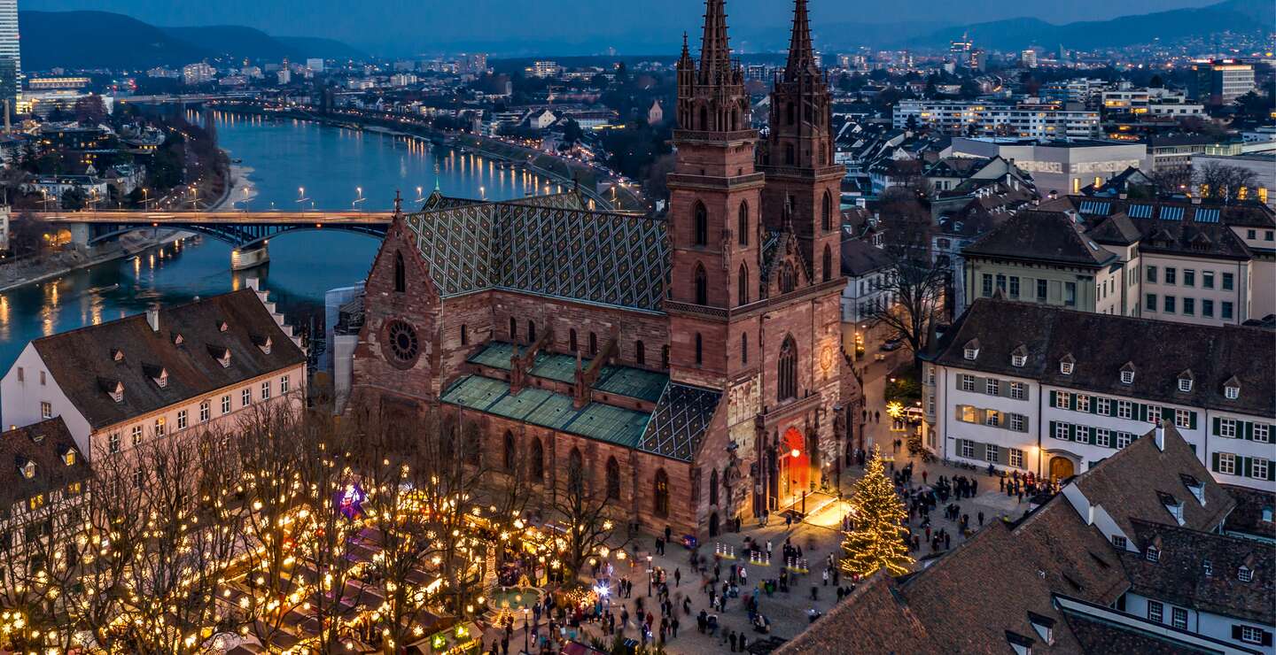 Winterlicher Weihnachtsmarkt mit beleuchtetem Dom und Fluss im Hintergrund | © Schwitzerland Tourismus/Jan Geerk