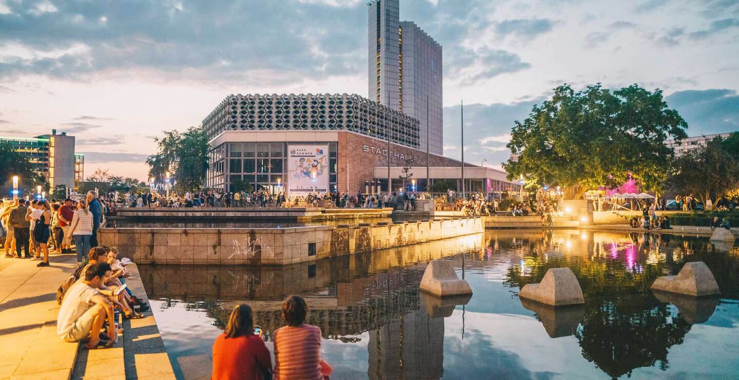 Chemnitz Stadthalle am Abend mit Brunnen und Menschen | © Ernesto Uhlmann