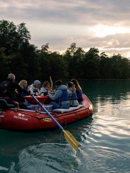 Personen sitzen auf einem Raft im Winter auf einem See und essen Raclette. | © Outdoor.ch
