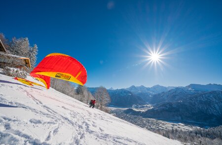 Person beim Paragliding im Schnee mit Sonne | © Mike Kaufmann