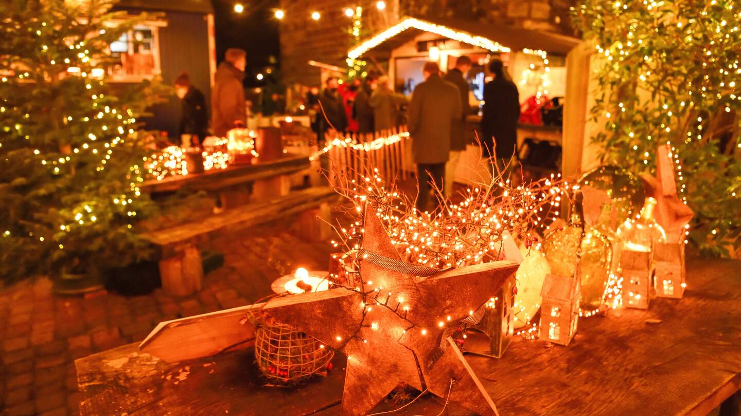 Funkelnde Lichter an Weihnachtsmarktständen mit einem alten Steinturm im Hintergrund | © KTG Karlsruhe Tourismus GmbH, Fabian von Poser