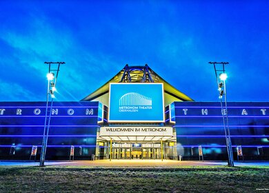 Das Metronom Theater Oberhausen von Vorne hell beleuchtet am Abend | © Semmel Concerts Entertainment GmbH