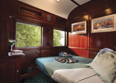 das Innere eines Schlafwagens in einem Zug, mit einem gemuetlich gemachten Bett und Holzverkleidungen an den Waenden | © DOOKPHOTO