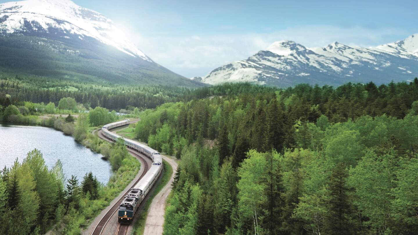 Der Canadian in Vogelperspektive, welcher durch die kanadische Landschaft mit Bergen und Wäldern fährt | © VIA Rail Canada