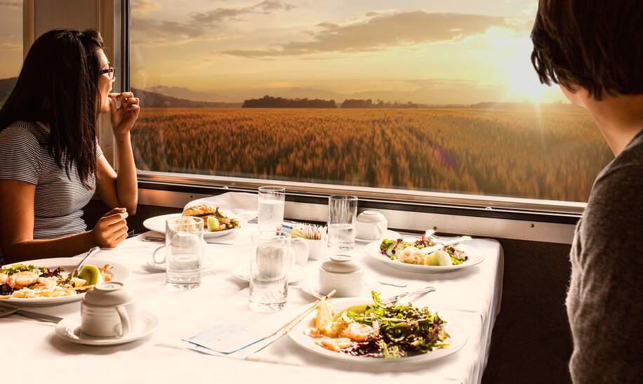 2 Menschen sitzen im Speisewagen beim Abendessen und schauen aus dem Fenster in den Sonnenuntergang | © Hewlett-Packard Company