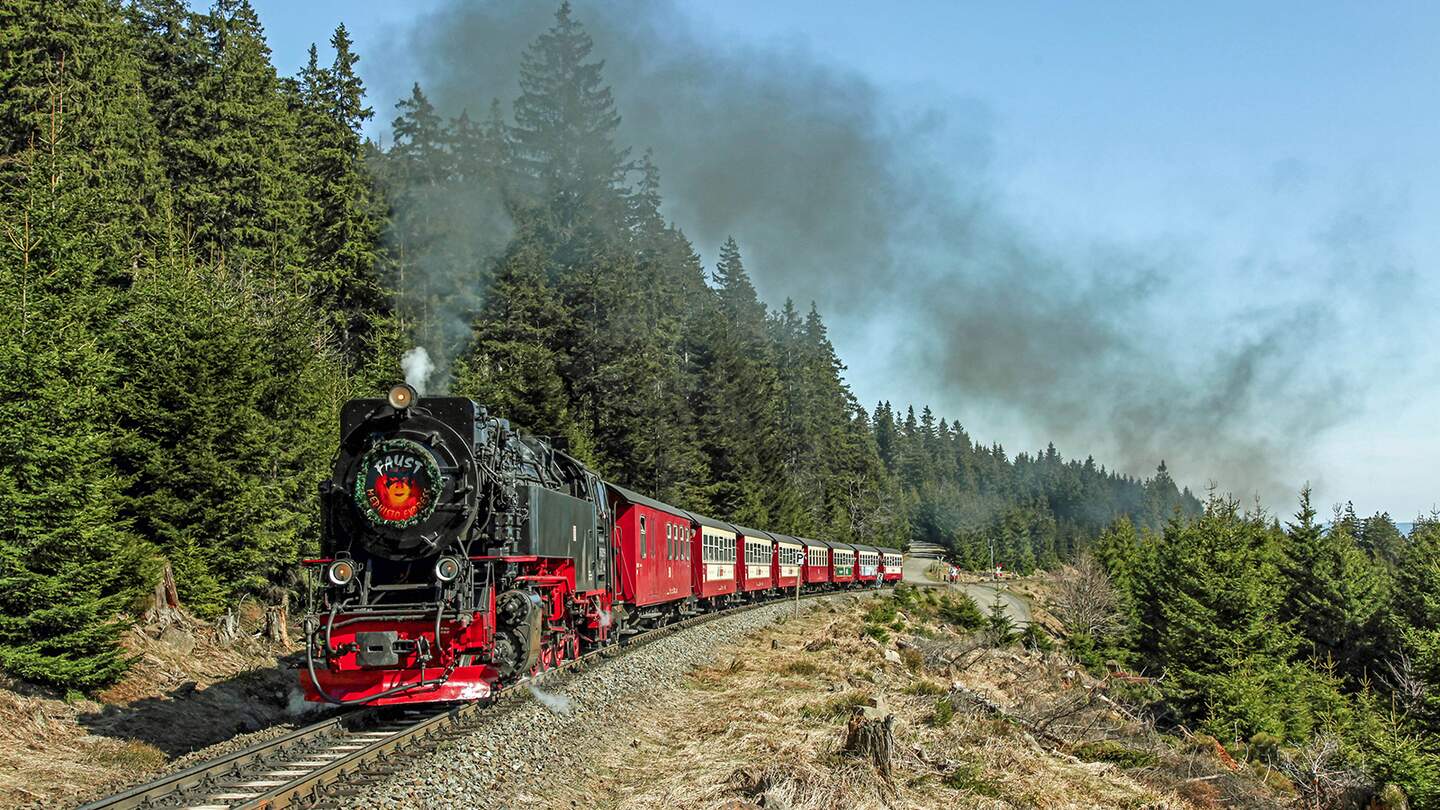 schwarze, vintage Dampflokomotive mit roten Verzierungen, die an einem Bahsteig steht.  | ©  HSB/Dirk Bahnsen