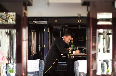 das Innere eines Orient-Express-Waggons, am Ende des Waggons ist ein Schaffner zu sehen  | © gettyimages.com/Neues Thema Helen Cathcart