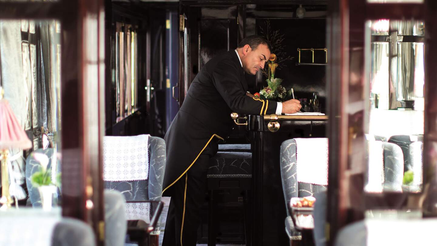 das Innere eines Orient-Express-Waggons, am Ende des Waggons ist ein Schaffner zu sehen  | © gettyimages.com/Neues Thema Helen Cathcart