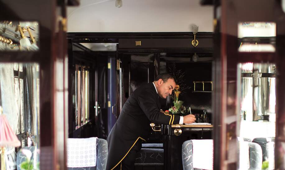 das Innere eines Orient-Express-Waggons, am Ende des Waggons ist ein Schaffner zu sehen  | © gettyimages.com/Neues Thema Helen Cathcart