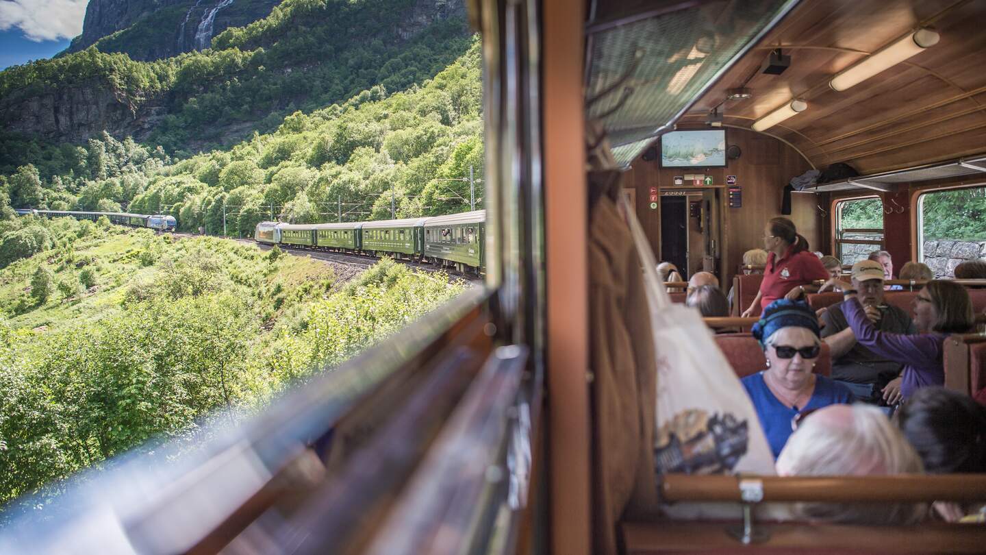  das Innere eines Zugwagens, aus dessen Fenstern die Fahrgaeste auf eine malerische Landschaft blicken | © Sverre Hjornevik