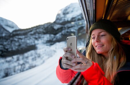 Eine Frau, die mit einem Smartphone ein Foto aus dem Zugfenster macht. | © Sverre Hjornevik