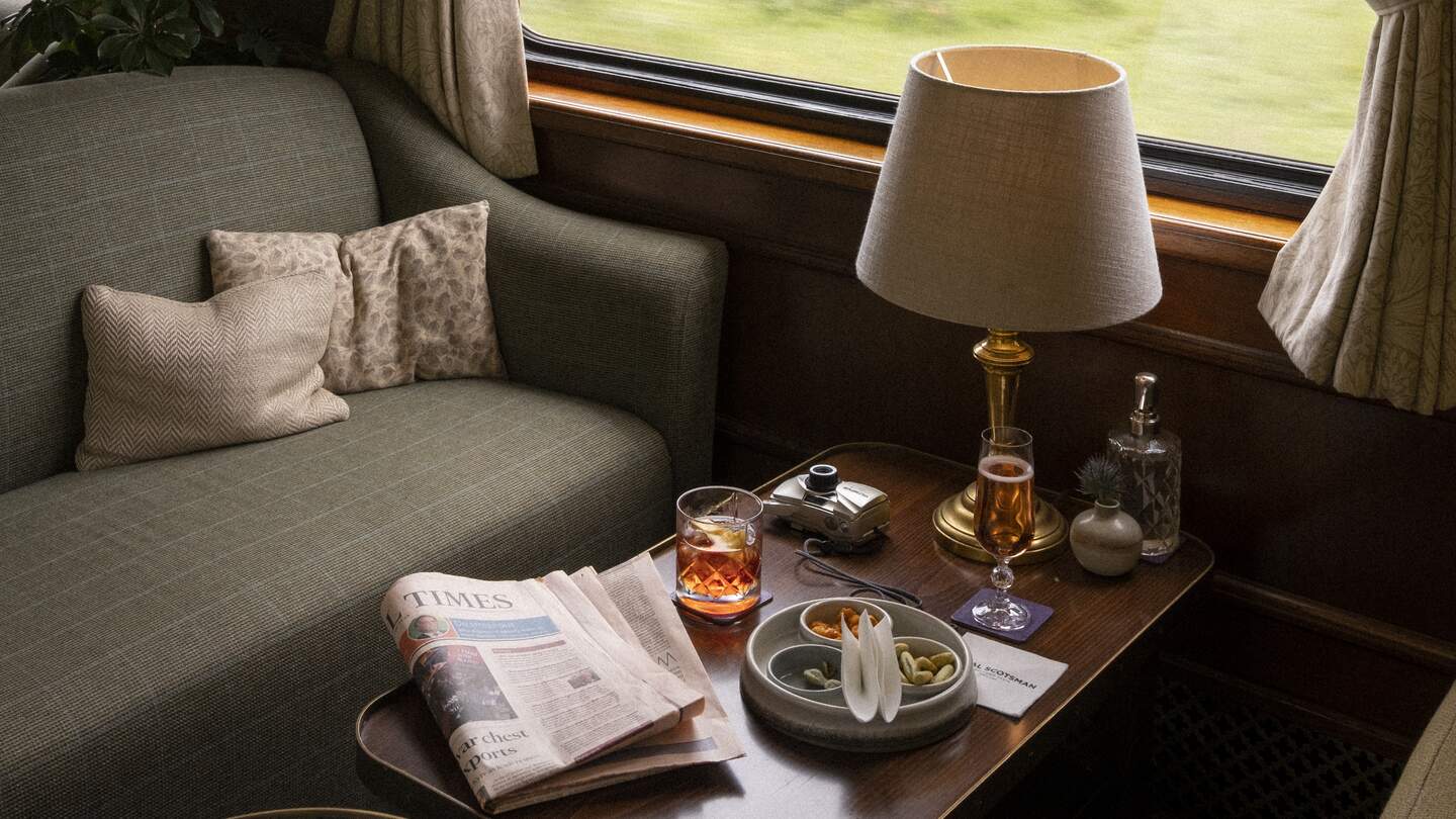Barwagen mit einem grünen Sofa und Getränken auf dem Tisch. | © belmond.com/The World from a Window