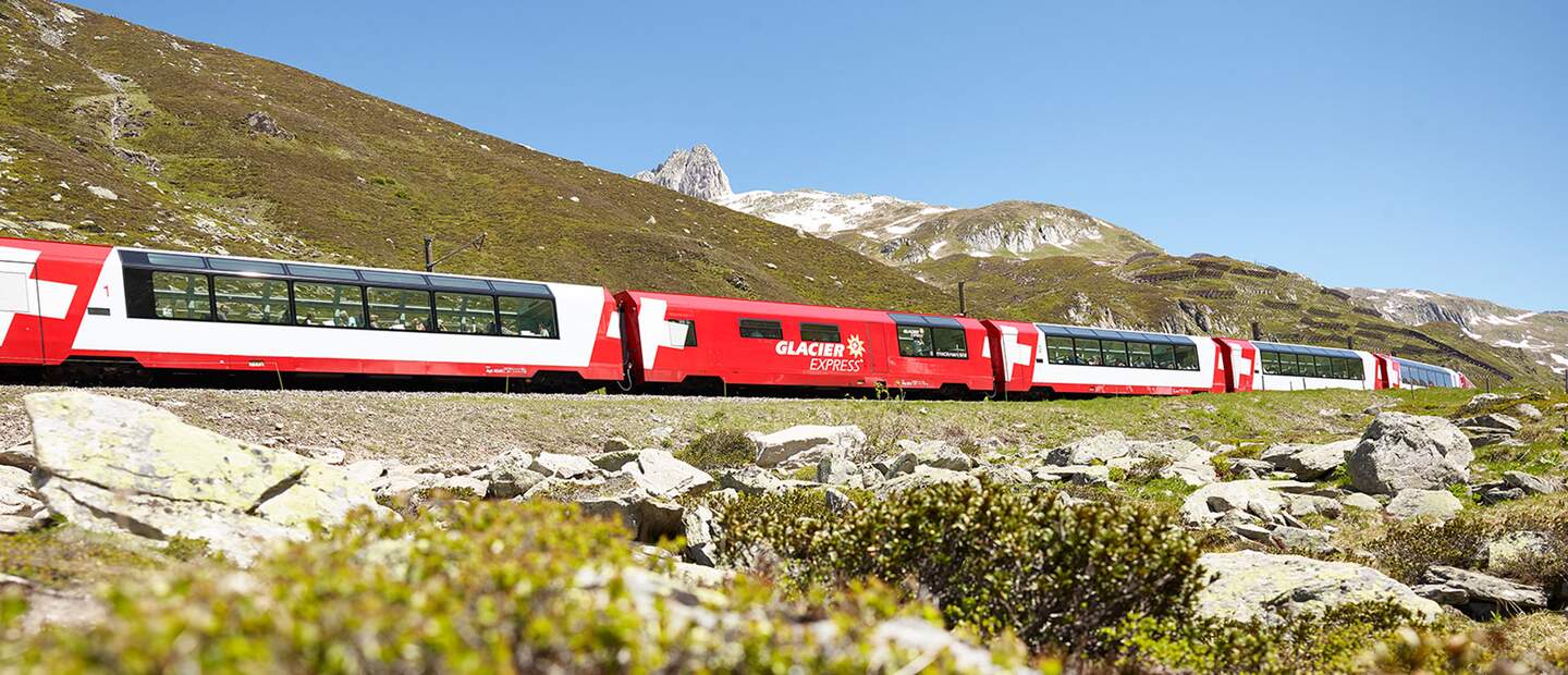 Der Glacier Express faehrt ueber den Oberalppass in den Schweizer Alpen im Fruehling | © Glacier Express AG/Stefan Schlumpf