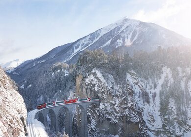 Der Glacier Express faehrt auf dem Landwasserviadukt in der Schweiz im Winter | © Glacier Express AG/Stefan Schlimpf