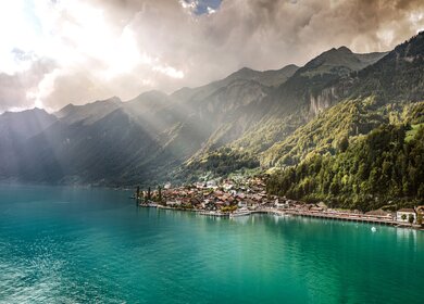 Der Brienzer See im Vordergrund eingerahmt von Bergen und derm Ort Brienz am Seeufer | © simon+kim, Zentralbahn