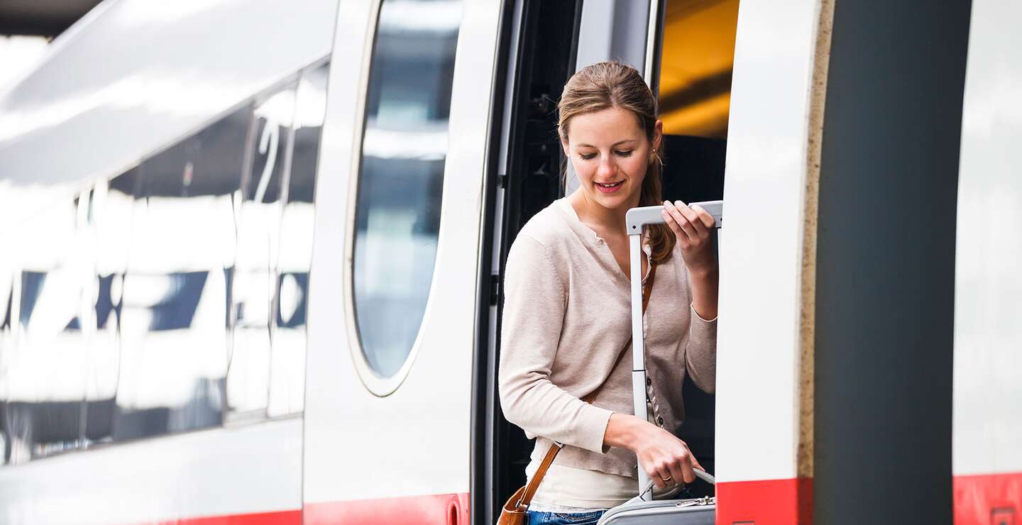 Junge Frau mit Rollkoffer steigt in einen ICE | © Gettyimages.com/ViktorCap