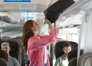 Eine Frau verstaut ihr Gepäck im Eurostar an Bord eines e320 auf der Fahrt nach Amsterdam | © John Adrian