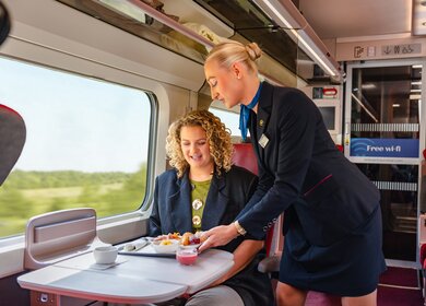 Ein Mitglied des Bordteams serviert eine Mahlzeit im Eurostar Premier | © Eurostar
