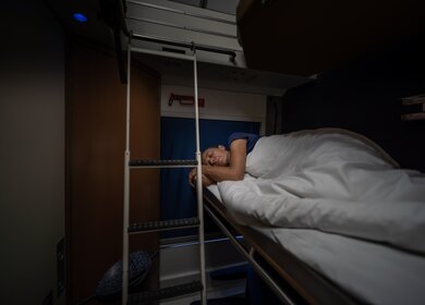 Frau schläft im Schlafwagen eines Nachzugs | © Gettyimages.com/amirphoto
