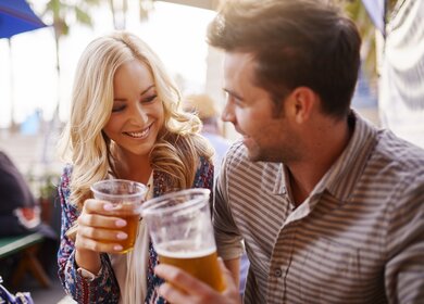 Paar, das Bier in Plastikbechern an der Bar im Biergarten | © Gettyimages.com/rez-art