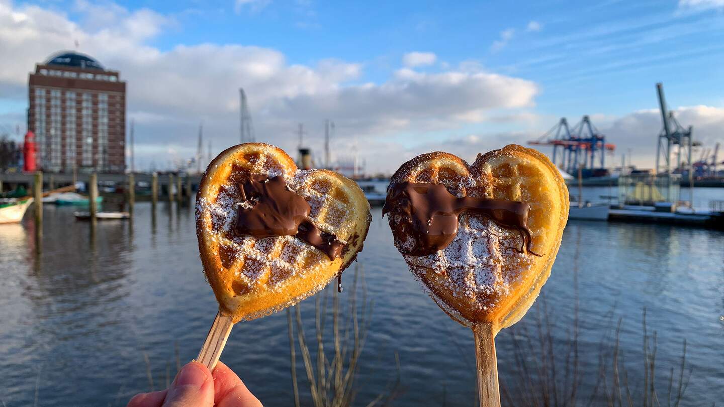 Hamurger Hafen an der Elbe. Zwei Herzwaffeln am Stil werden gehalten. | © Gettyimages.com/lapasmile