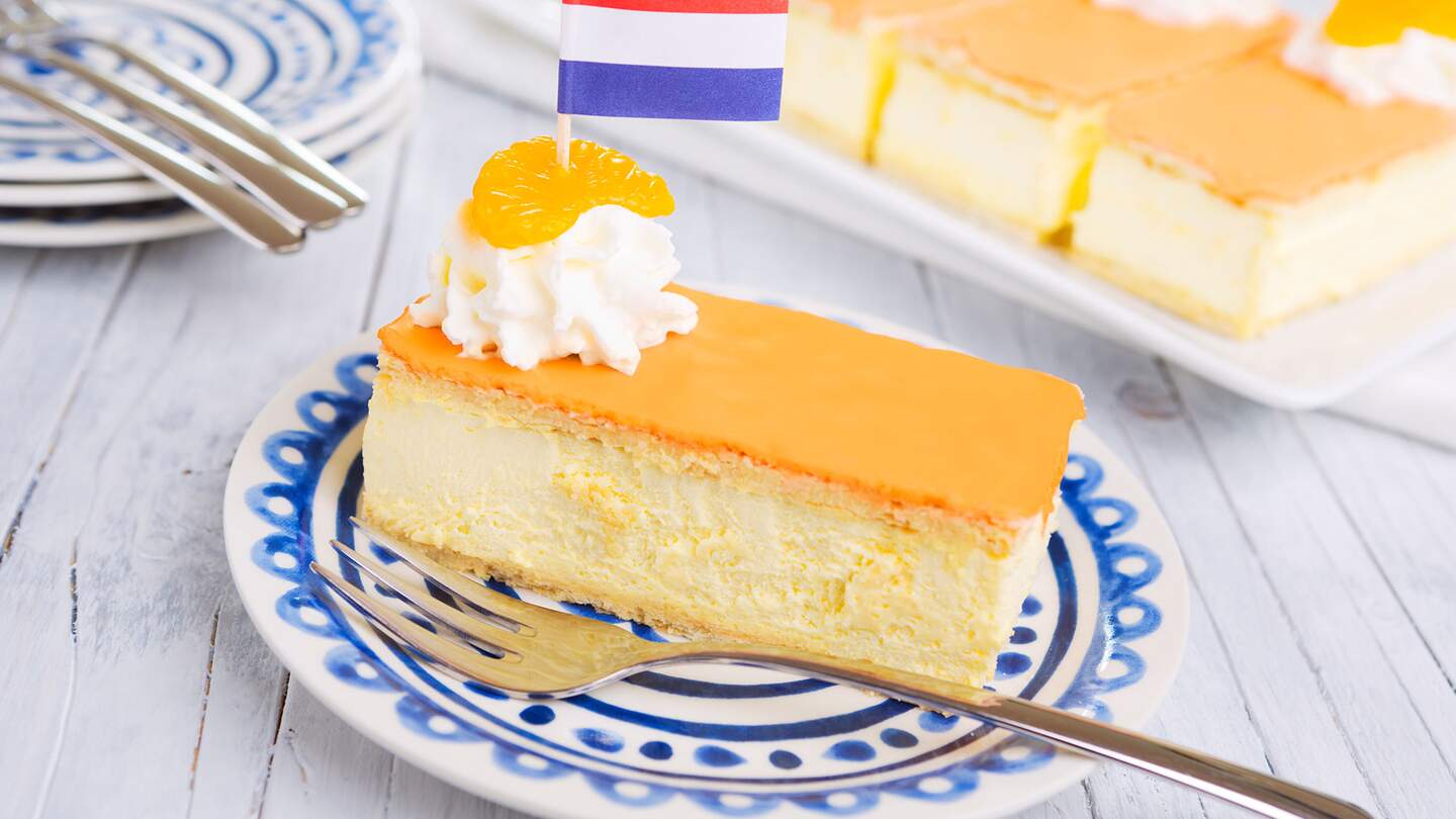 Ein orangefarbenes Tompouce, traditionelles hollaendisches Gebaeck, auf einem Teller. Der orangefarbene Zuckerguss auf dem Tompouce ist typisch für den Koeniginnentag | © Gettyimages.com/Sara Winter