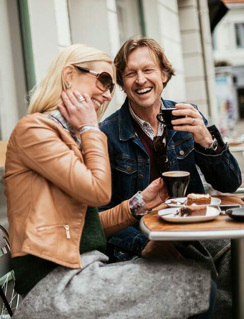 Paar trinkt Kaffe und ist Kuchen an einem Tisch im Assenbereich eines Cafès | © Gettyimages.com/Geber86