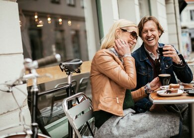 Paar trinkt Kaffe und ist Kuchen an einem Tisch im Assenbereich eines Cafès | © Gettyimages.com/Geber86