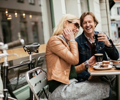 Paar trinkt Kaffe und ist Kuchen an einem Tisch im Assenbereich eines Cafès | © Gettyimages.com/Geber86