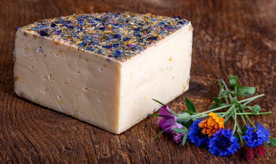 Bergkaese mit getrockneten Blumen auf einem Holzbrett | © Gettyimages.com/bernjuer