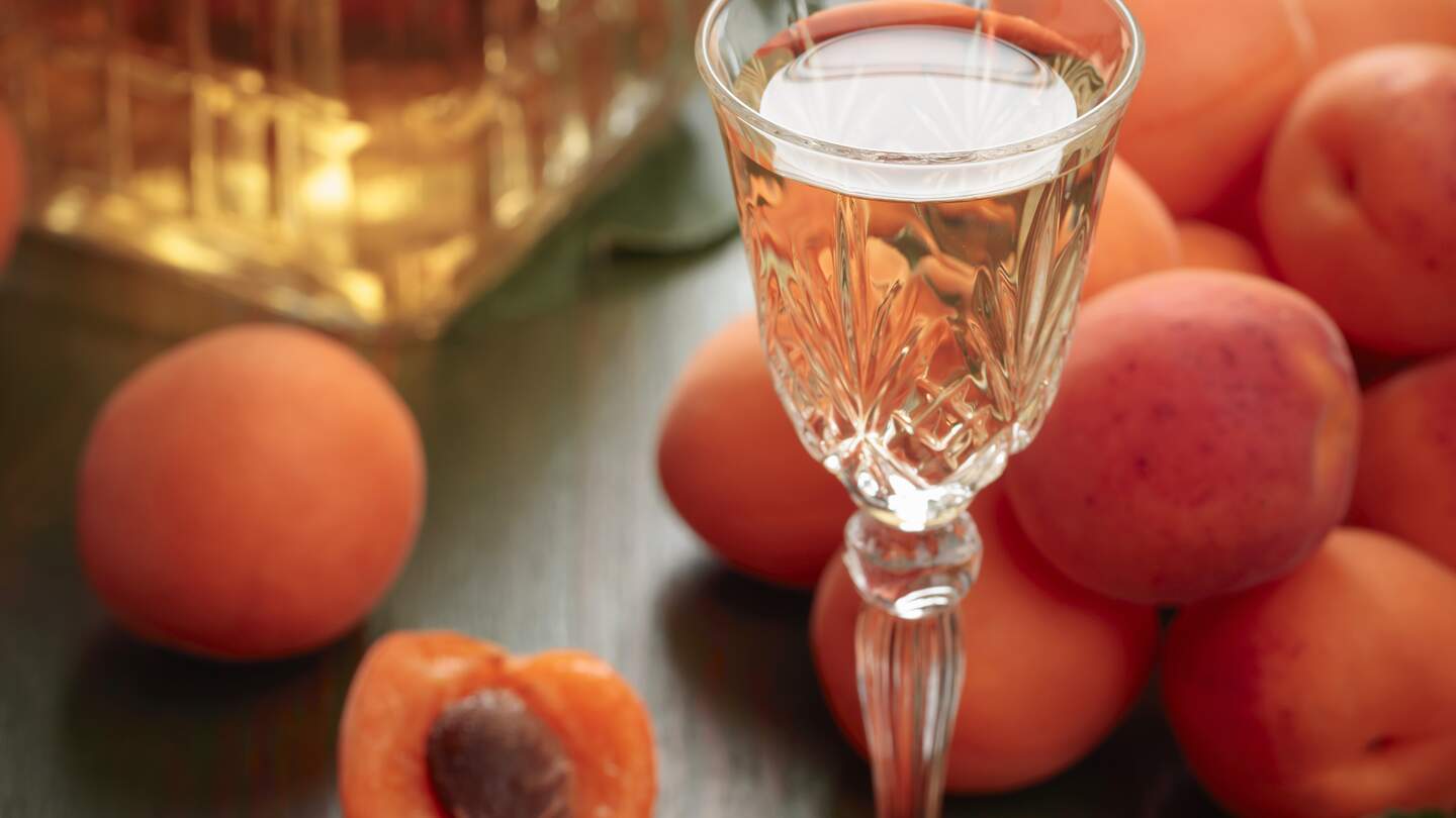 Aprikosenlikoer mit frischen Fruechten auf einem Holztisch | © Gettyimages.com/igorr1