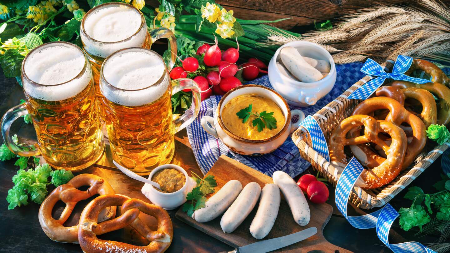 Bayerische Wurst mit Brezeln, suessem Senf und Bierkruege auf rustikalen Holztisch | © Gettyimages.com/Alexander Raths