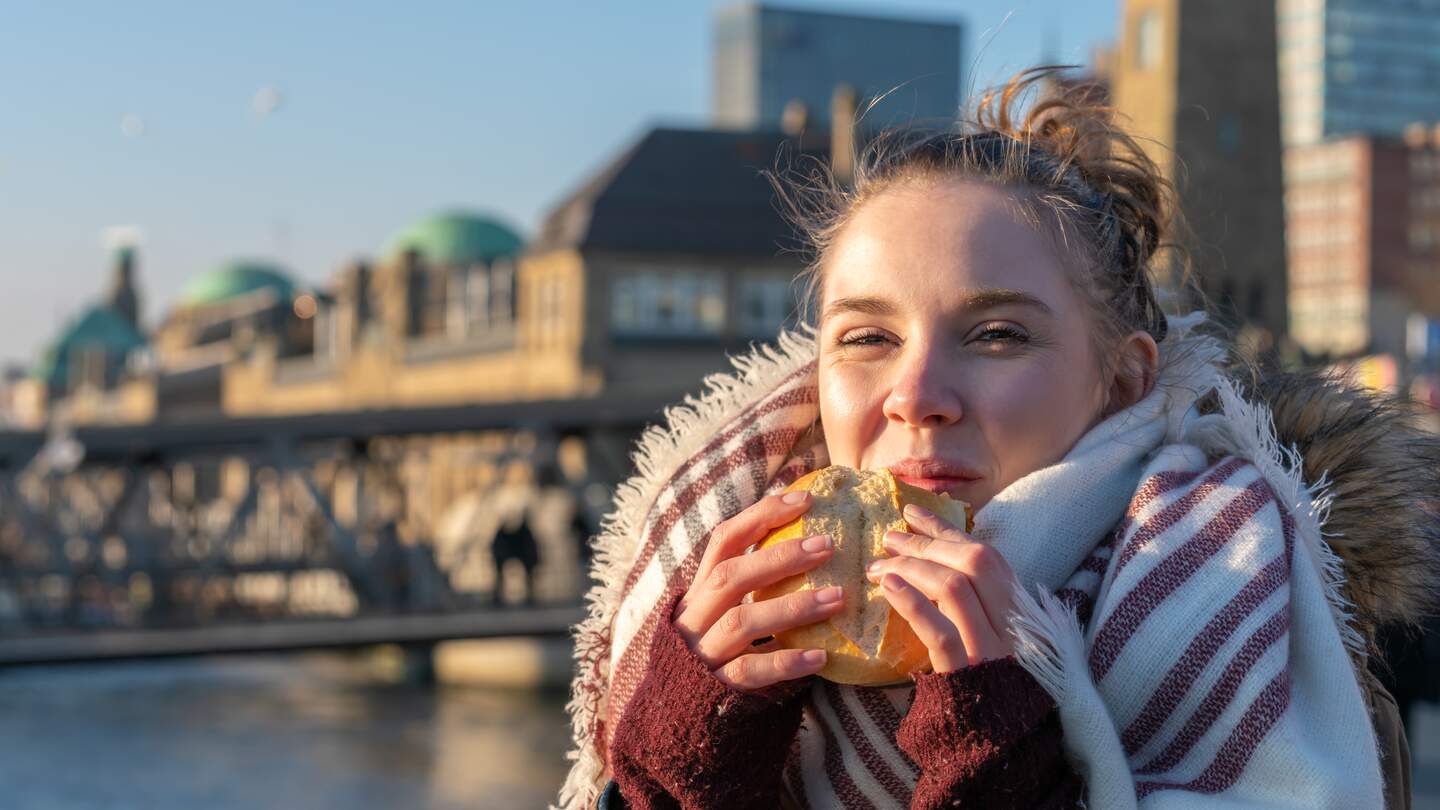 Eine Frau geniesst ein Fischbroetchen im Hamburger Hafen | © Gettyimages.com/Jens Rother