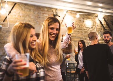 Zwei Frauen tanzen zuammen mit jeweils einem Becher Bier in der Hand | © Gettyimages.com/franckreporter